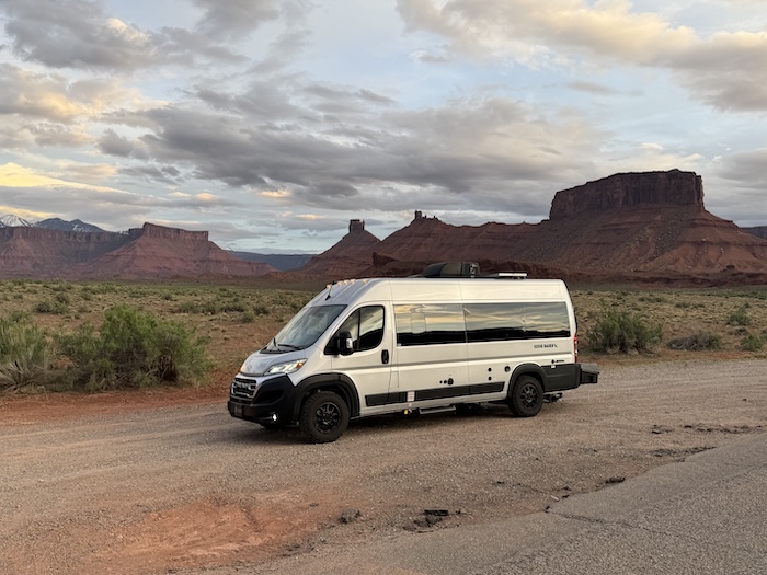 White camper van parked in a vast desert landscape with red rock formations